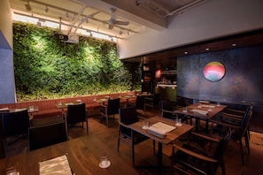 Un restaurante con pared verde, mesas y sillas de madera.
