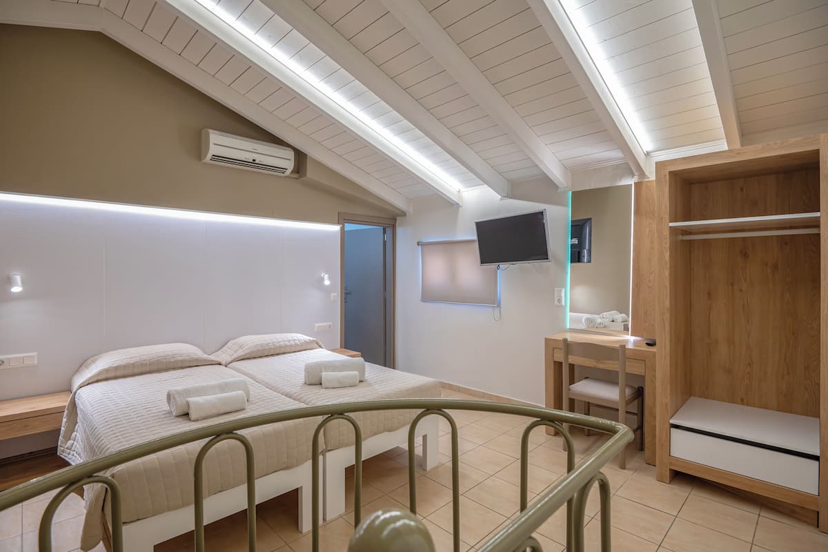 A hotel room with a bed, a desk, a TV, and a wardrobe.
