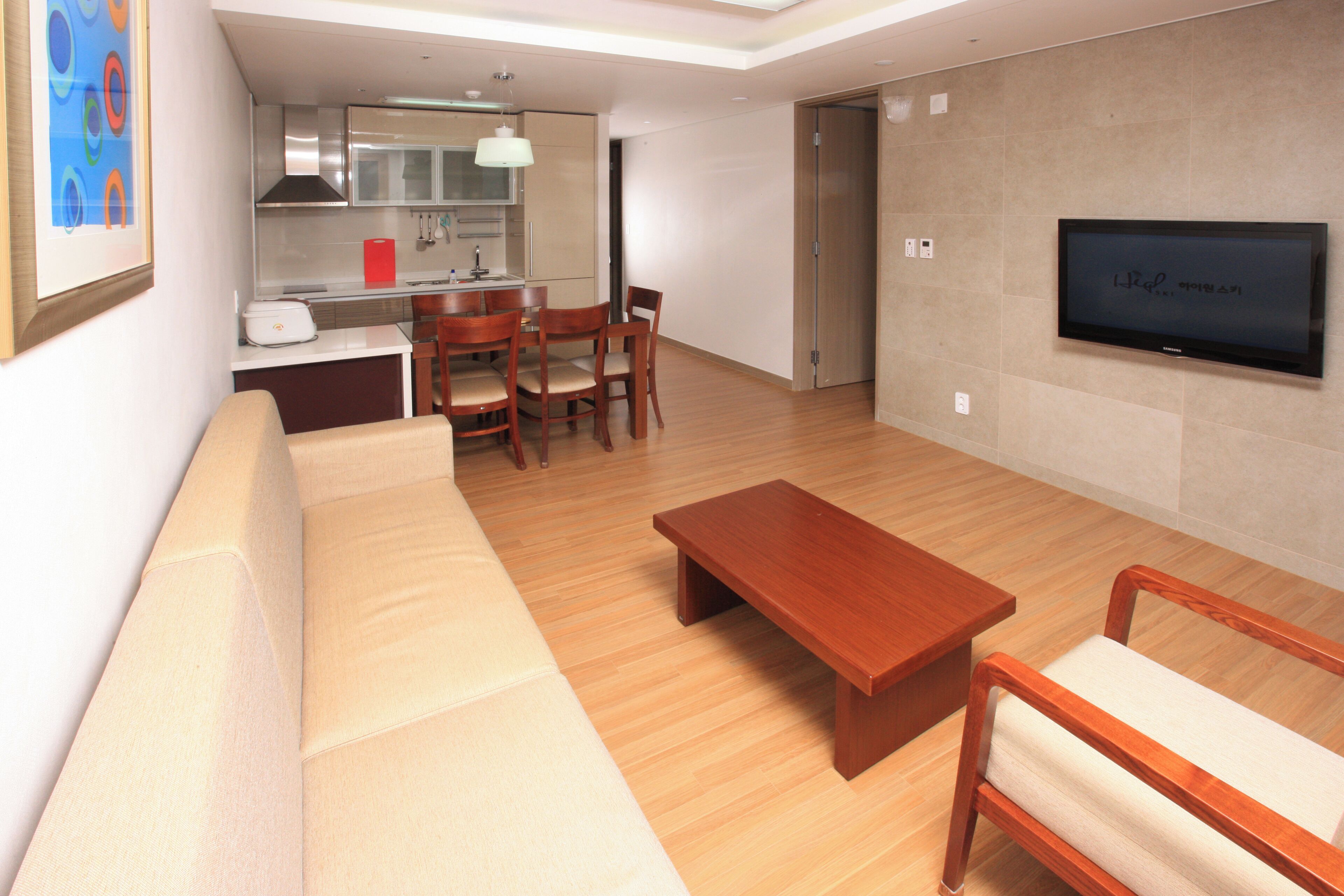 Una sala de estar con un sofá, una mesa de centro de madera y un televisor montado en la pared.