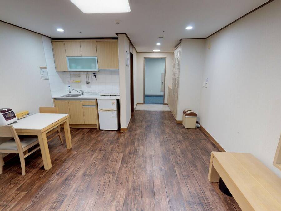 A compact kitchen with wooden flooring, a dining table, and a microwave.