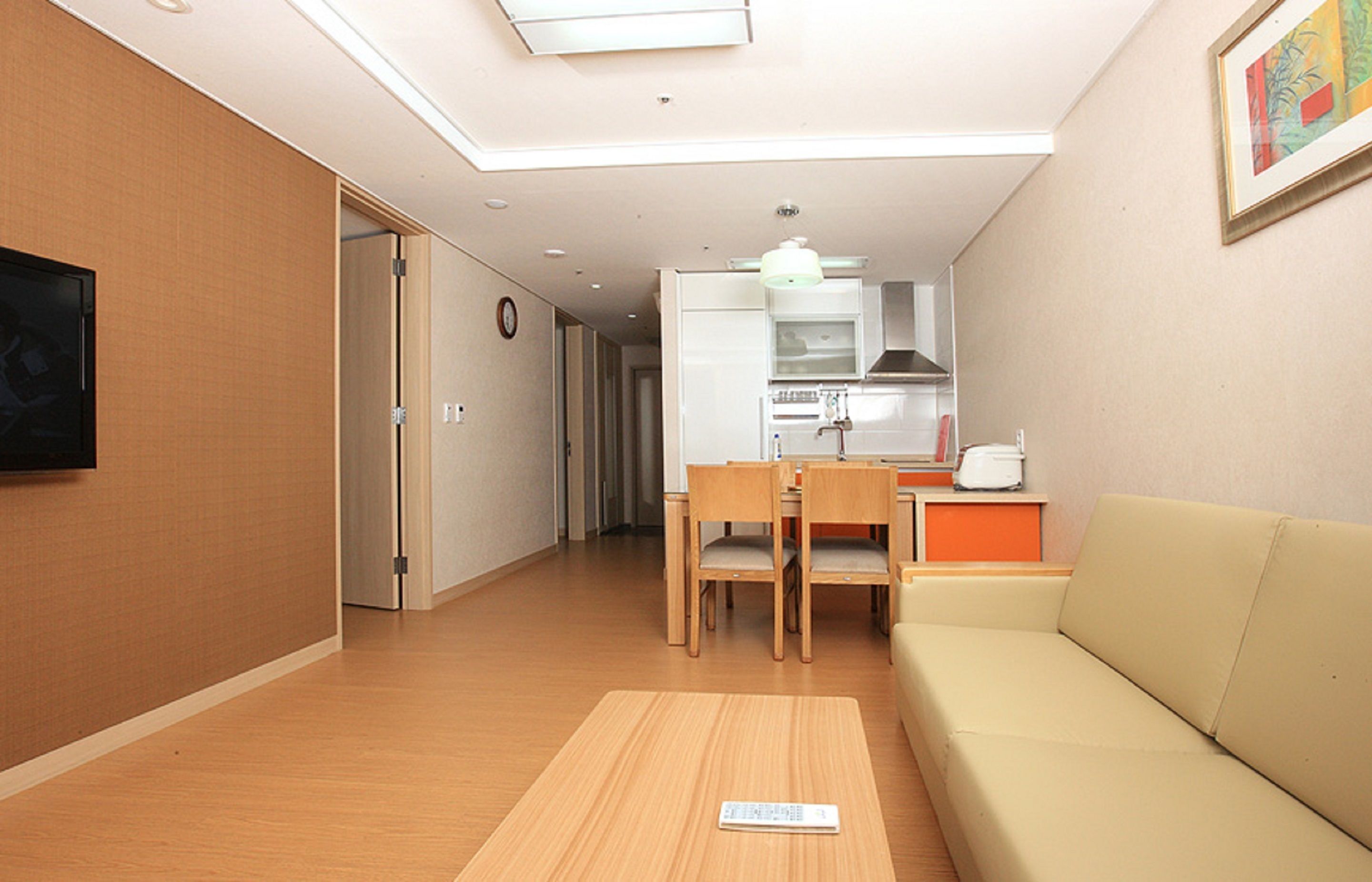 A modern living room with a sofa, a wooden table, and a TV on the wall.