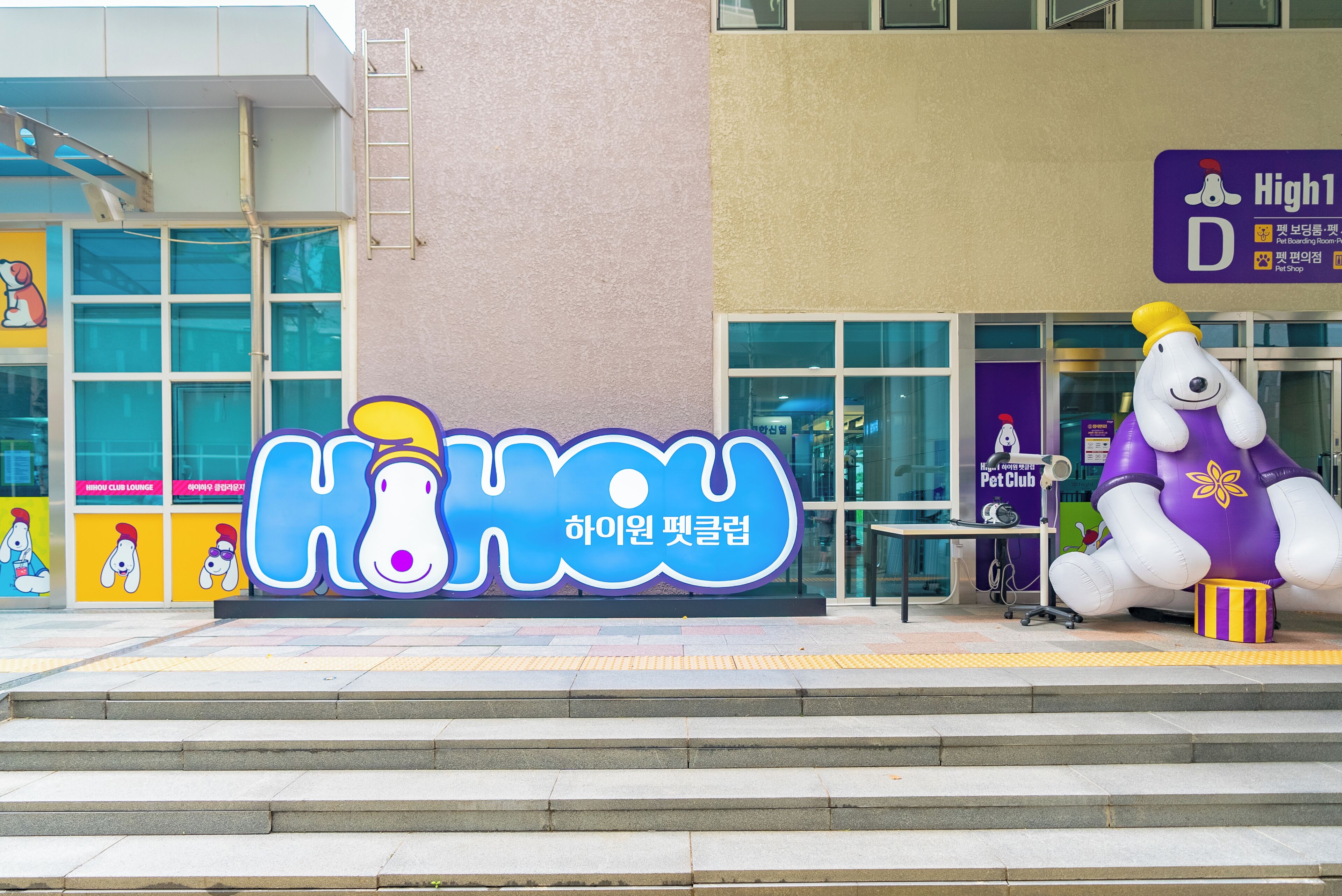 A building with a large 'HOU' sign, a pet shop, and a dog statue.