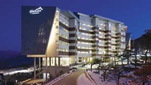 Ein mehrstöckiges Hotel mit einem auffälligen Schild 'Mountain Condominium', das ein modernes Architekturdesign mit großen Fenstern und einem gut beleuchteten Eingang zeigt.