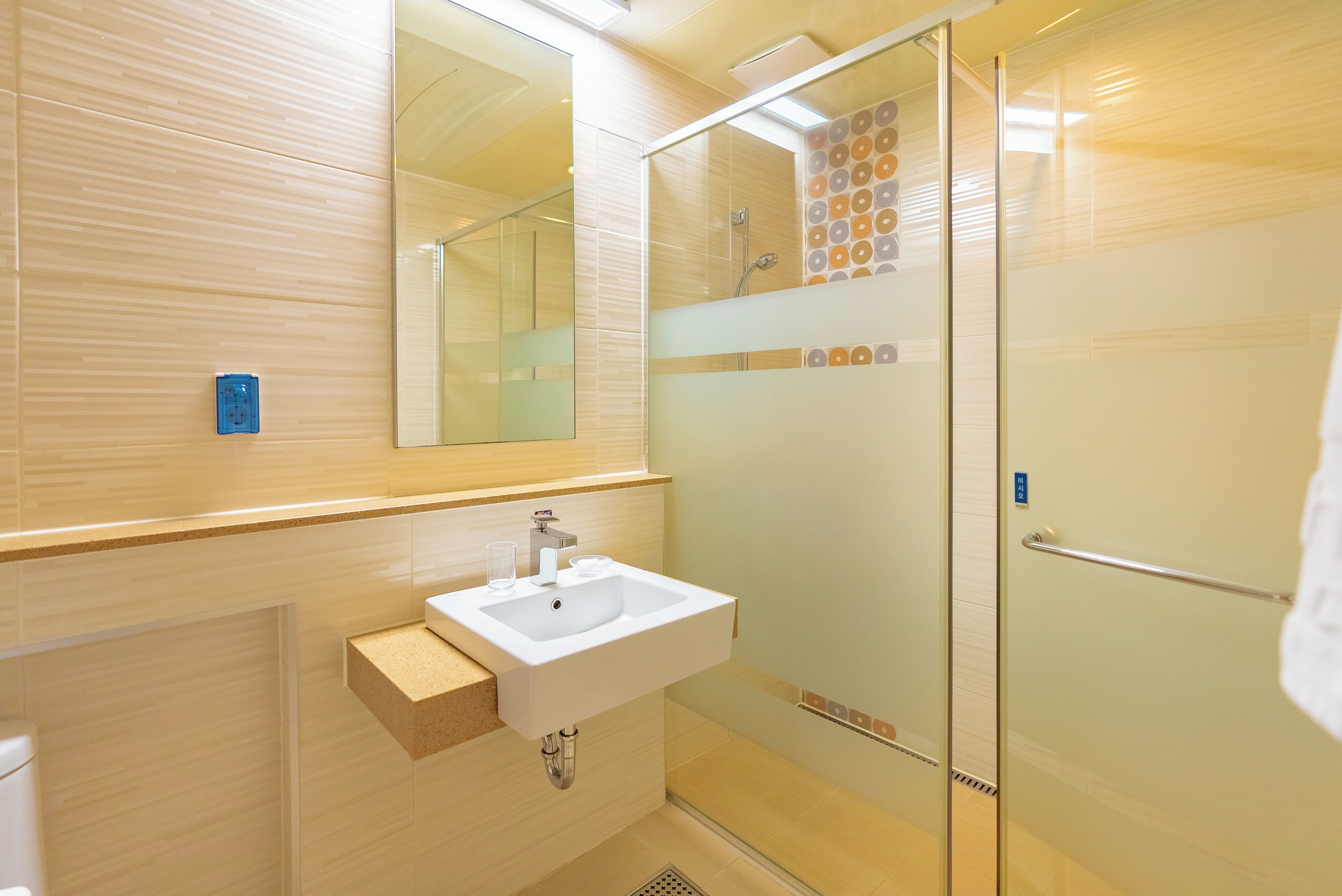 A modern bathroom with a glass shower enclosure, a sink with a mirror above, and a towel rack.