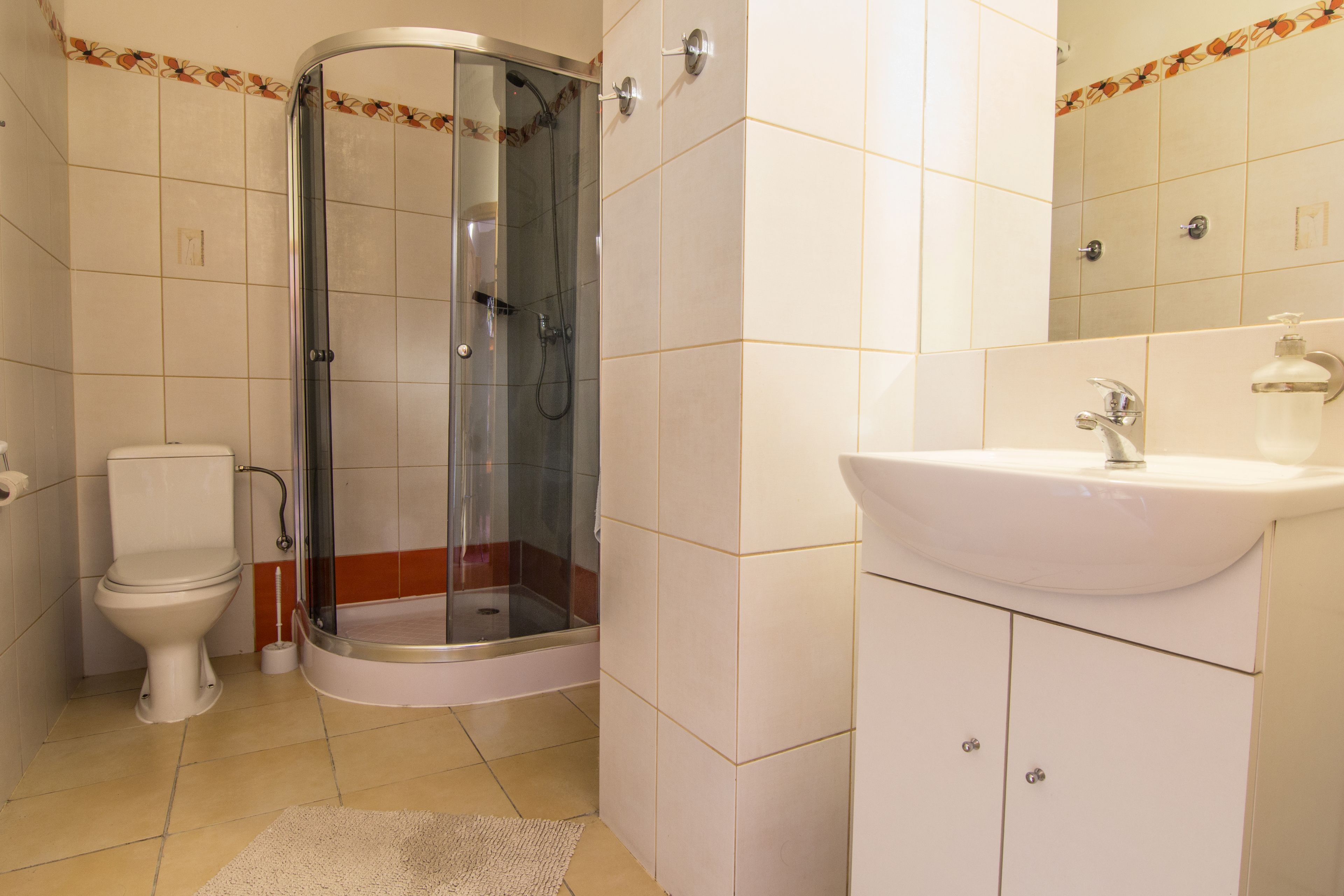 Un baño con ducha de vidrio, inodoro y lavamanos con armarios.