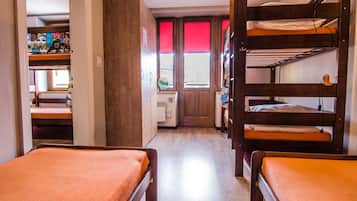 Un dormitorio con literas, un escritorio y una ventana con persianas rojas.