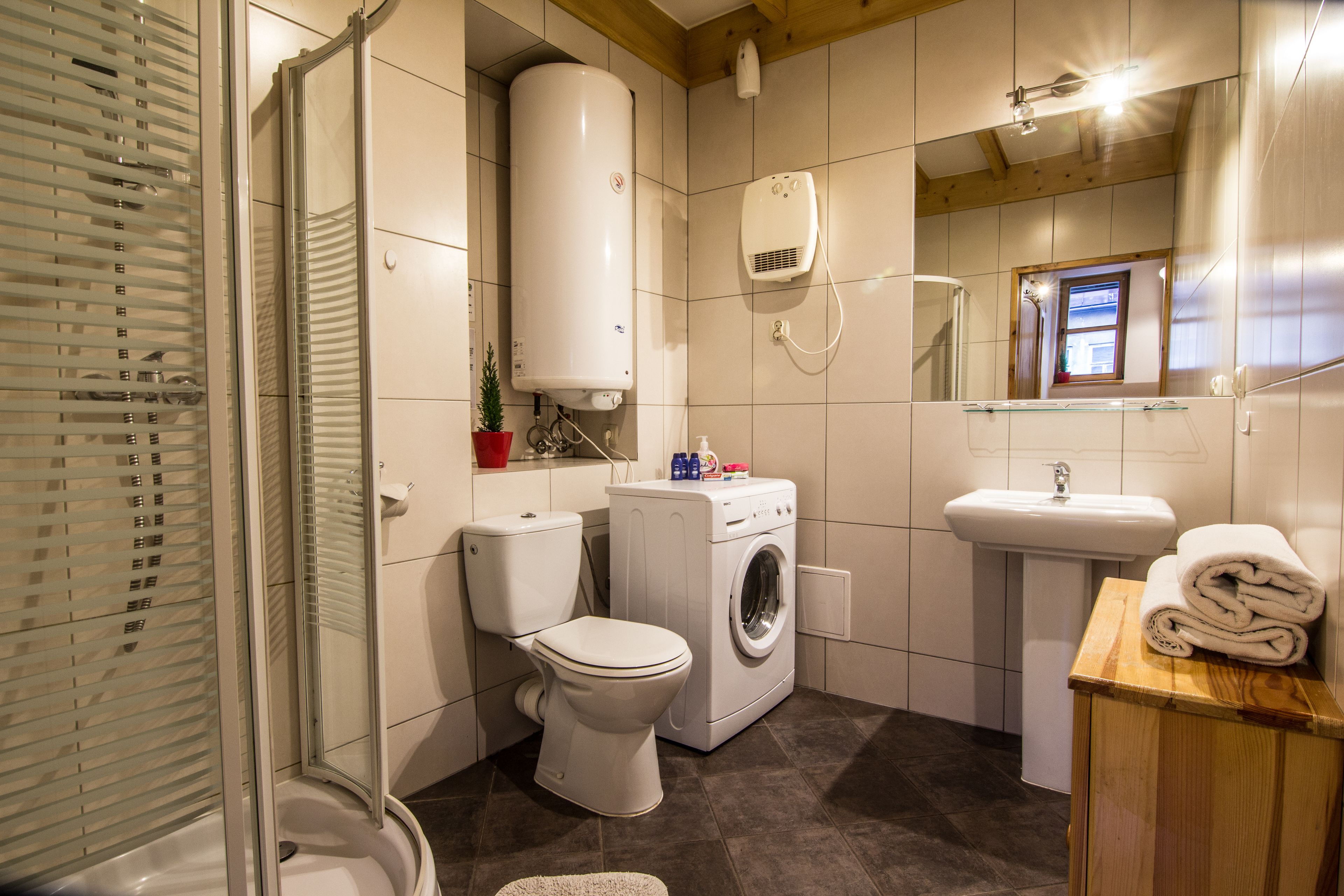 A compact bathroom with a toilet, washing machine, and sink.