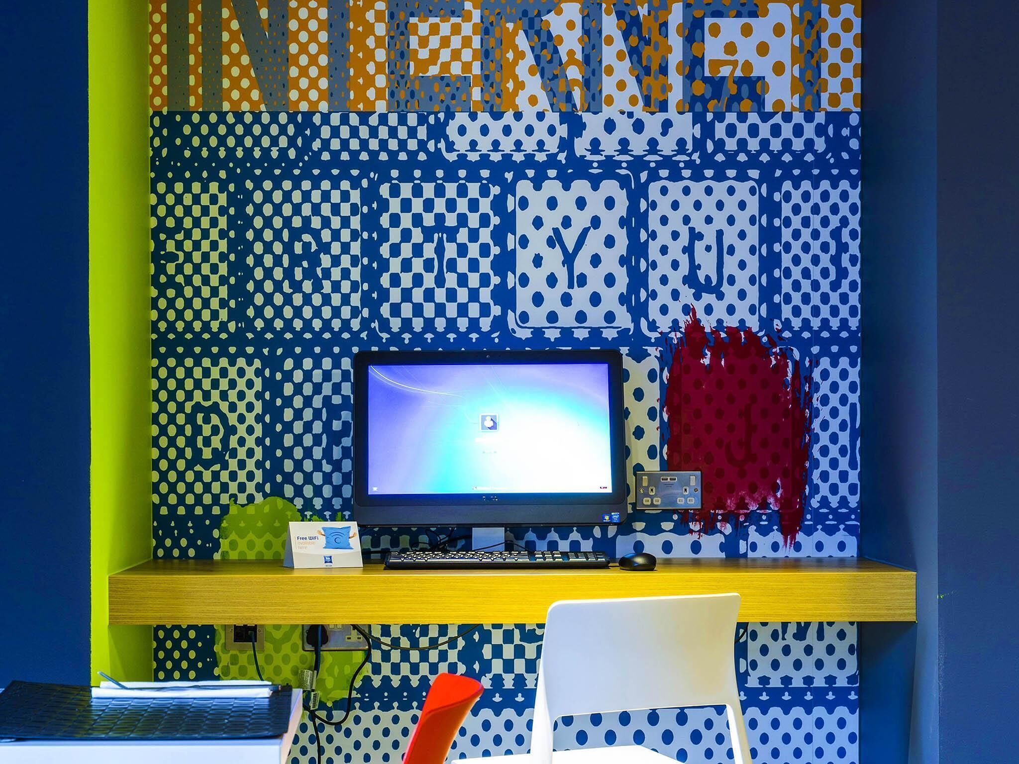 A room with a computer desk, a chair, and a wall with a polka dot pattern.