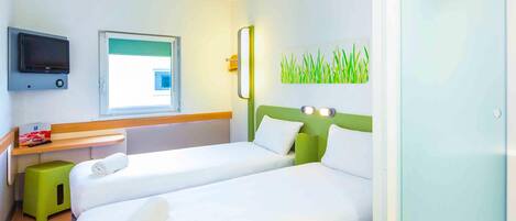 A hotel room with two beds, a TV, a window, and a green wall decoration.