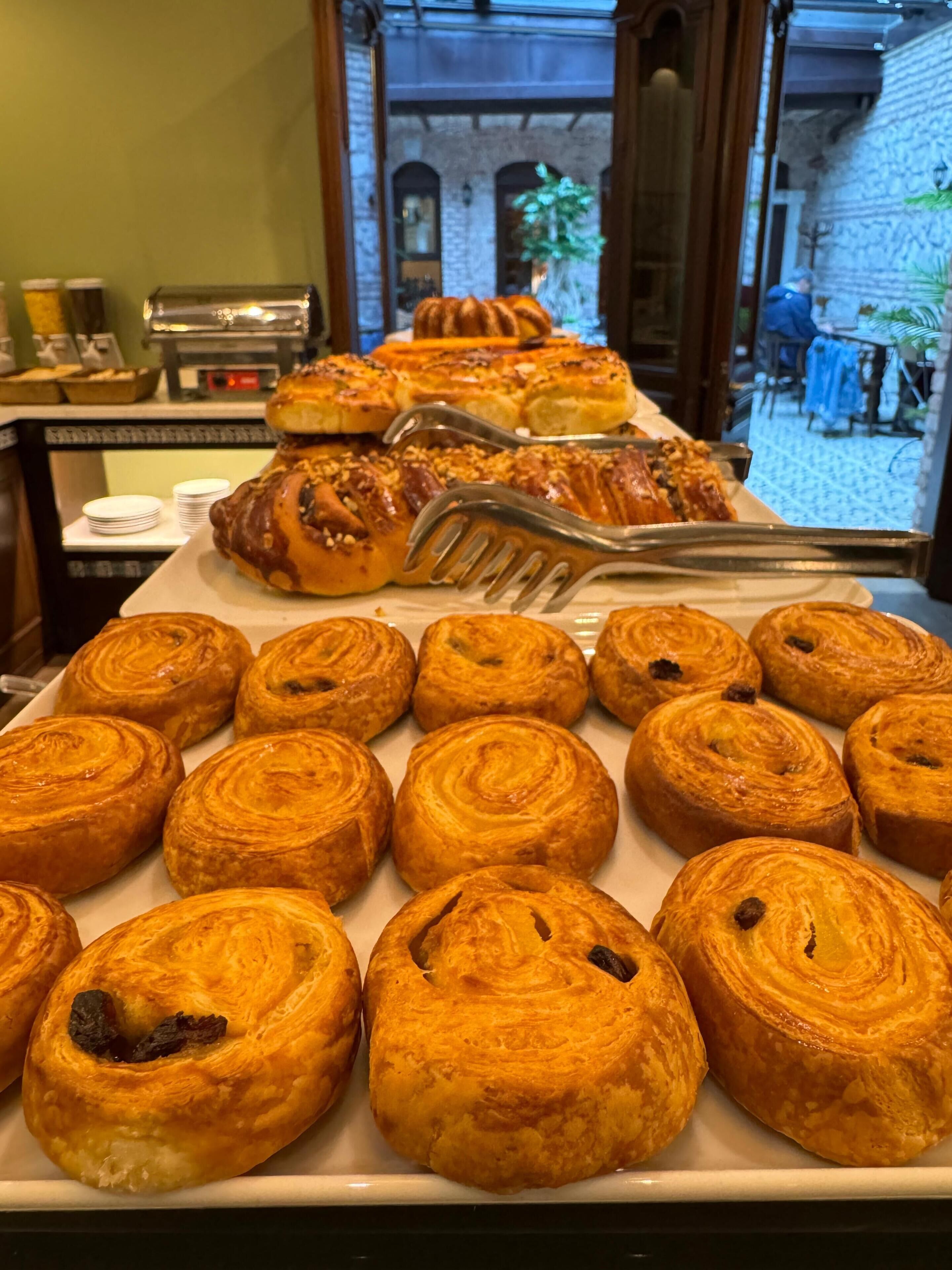 Ein Frühstücksbuffet mit verschiedenen Backwaren und Blick auf den Innenhof.