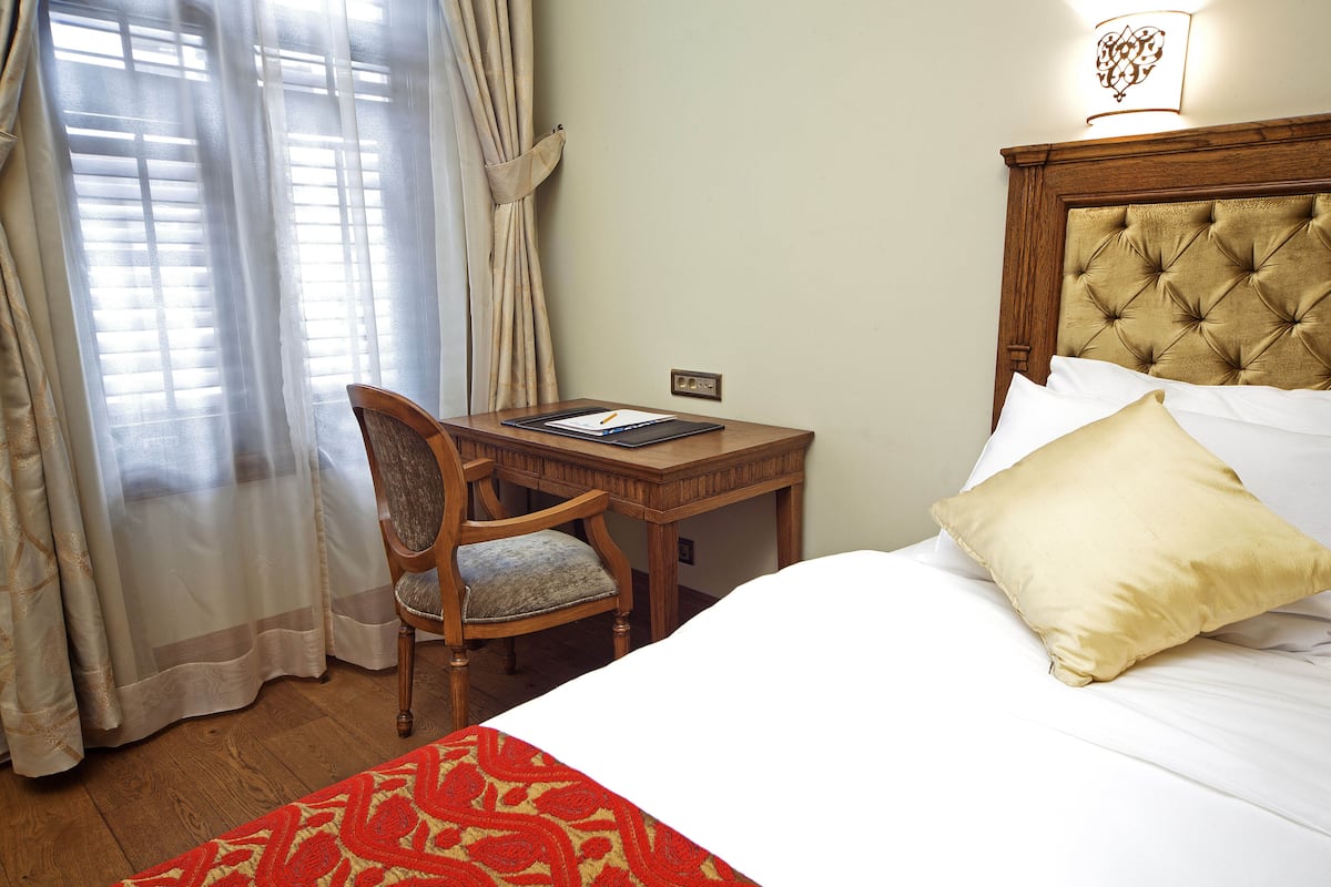 A hotel room with a bed, a desk, and a chair.