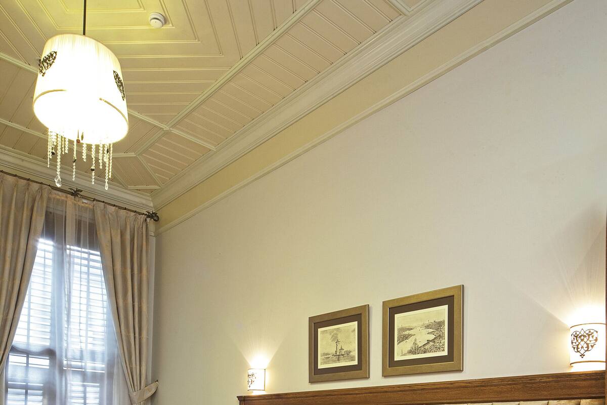 A hotel room with a large bed, two bedside tables, a wooden headboard, and a chandelier.