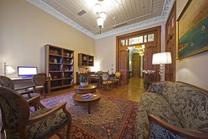 Ein geräumiges Wohnzimmer mit einer großen Holzbibliothek, einem bequemen Sofa, einem Couchtisch und einem gemusterten Teppich.