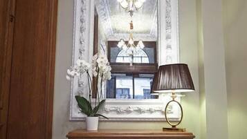 A wooden console table with a vase of white orchids, a lamp, and a mirror with a decorative frame.