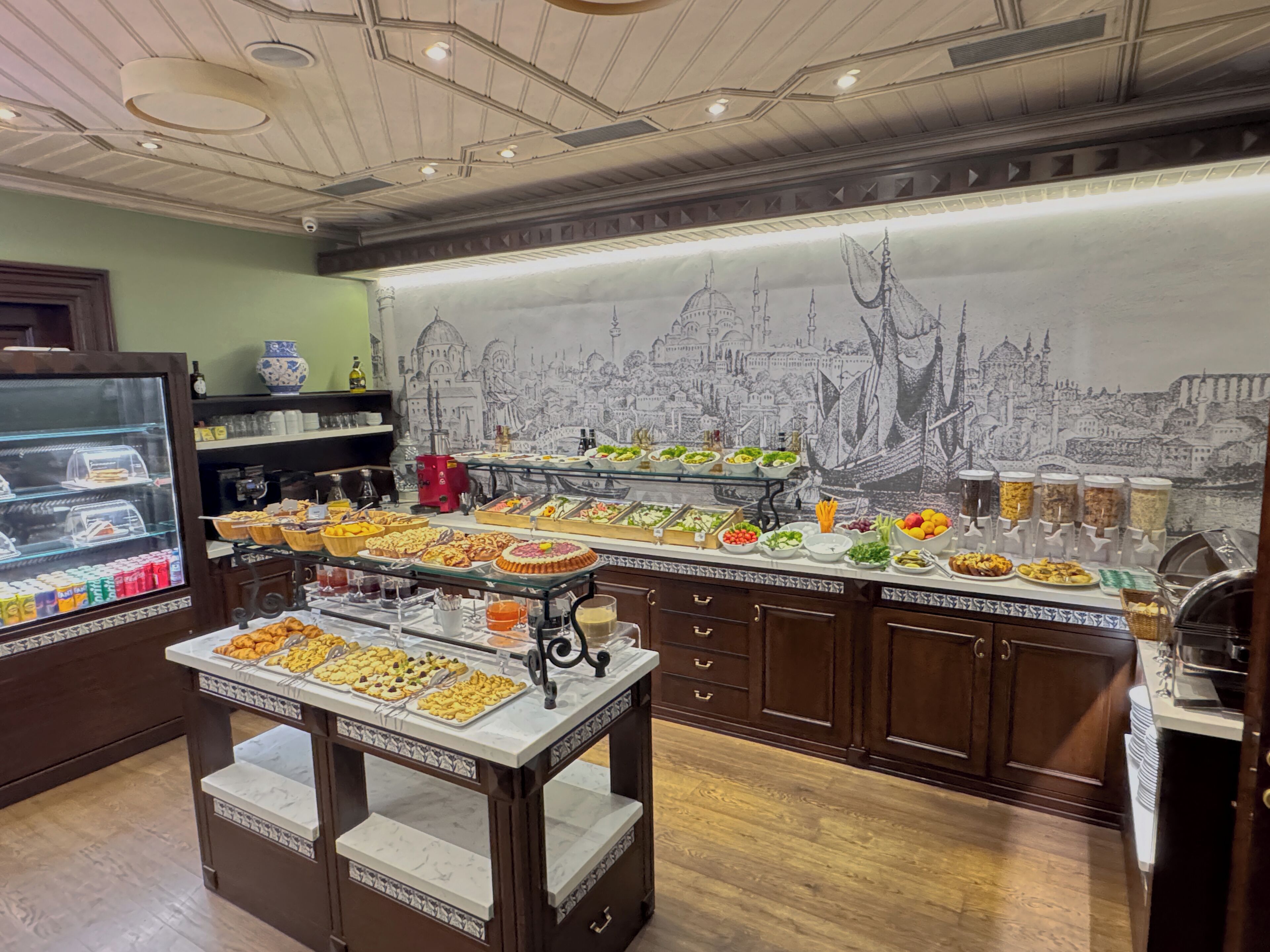 A buffet area with various food options and a cityscape mural on the wall.