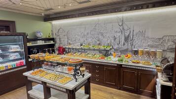 A buffet area with various food options and a cityscape mural on the wall.