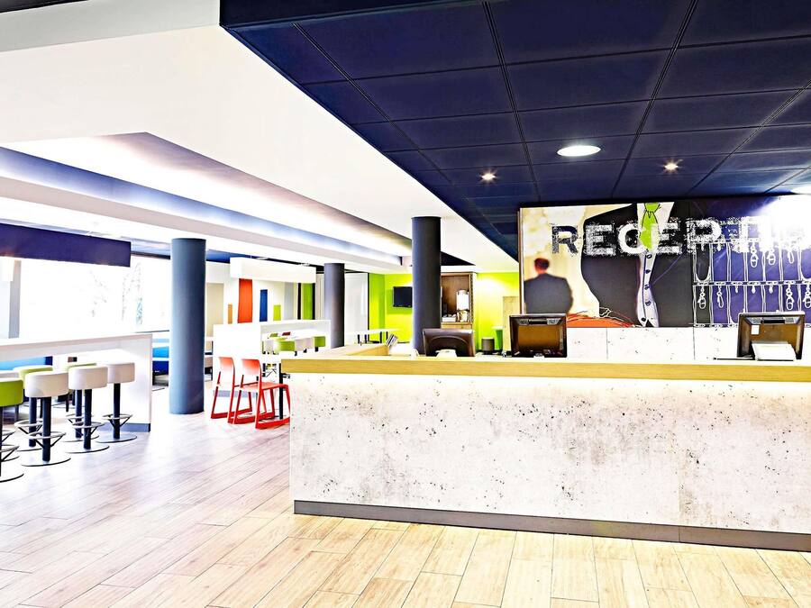 Un espace d’accueil moderne comprenant un comptoir, des sièges et une grande affiche.