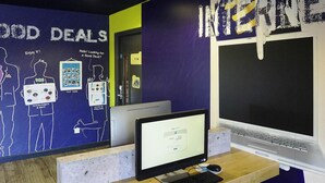 A computer desk with a monitor, keyboard, and mouse. There is a poster on the wall with text and images.