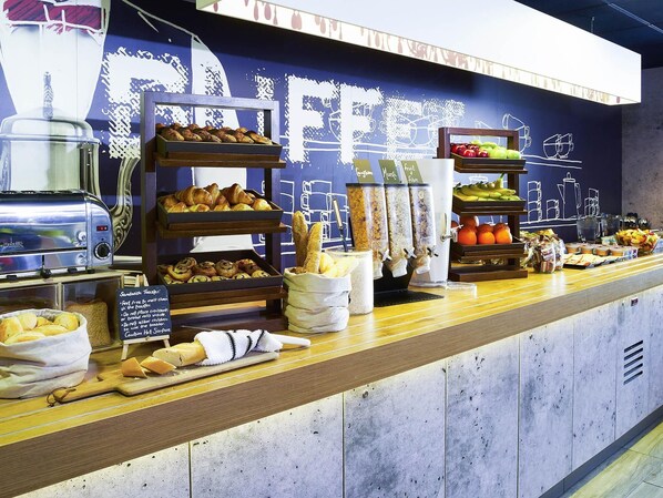 A breakfast buffet with various food items, a toaster, and a chalkboard with menu options. - ibis budget Birmingham Centre (Birmingham)