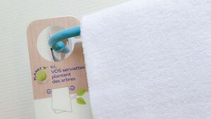 A tag attached to a white towel with a wooden background and a blue handle.