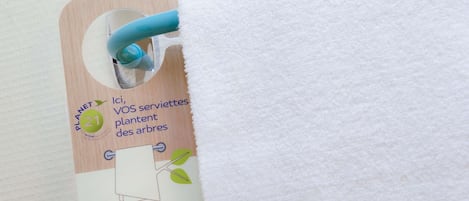 A tag attached to a white towel with a wooden background and a blue handle.