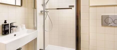 A modern bathroom with a glass-enclosed shower, a white sink with a mirror above it, and a wall-mounted control panel.