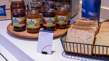 Una presentación de tarros de miel Le Berger Fruits, una tostadora y una cesta de pan sobre una encimera.