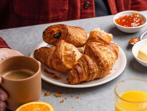 A plate with croissants and a cup of coffee, a glass of orange juice, and a bowl of jam. - ibis budget Leeds Centre Royal Armouries Museum (Leeds)