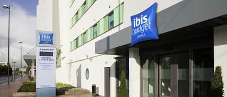 Een moderne hotelentree met een bordje voor ibis budget hotels.