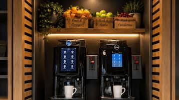 Una estación de café con dos máquinas de espresso y una variedad de frutas frescas.