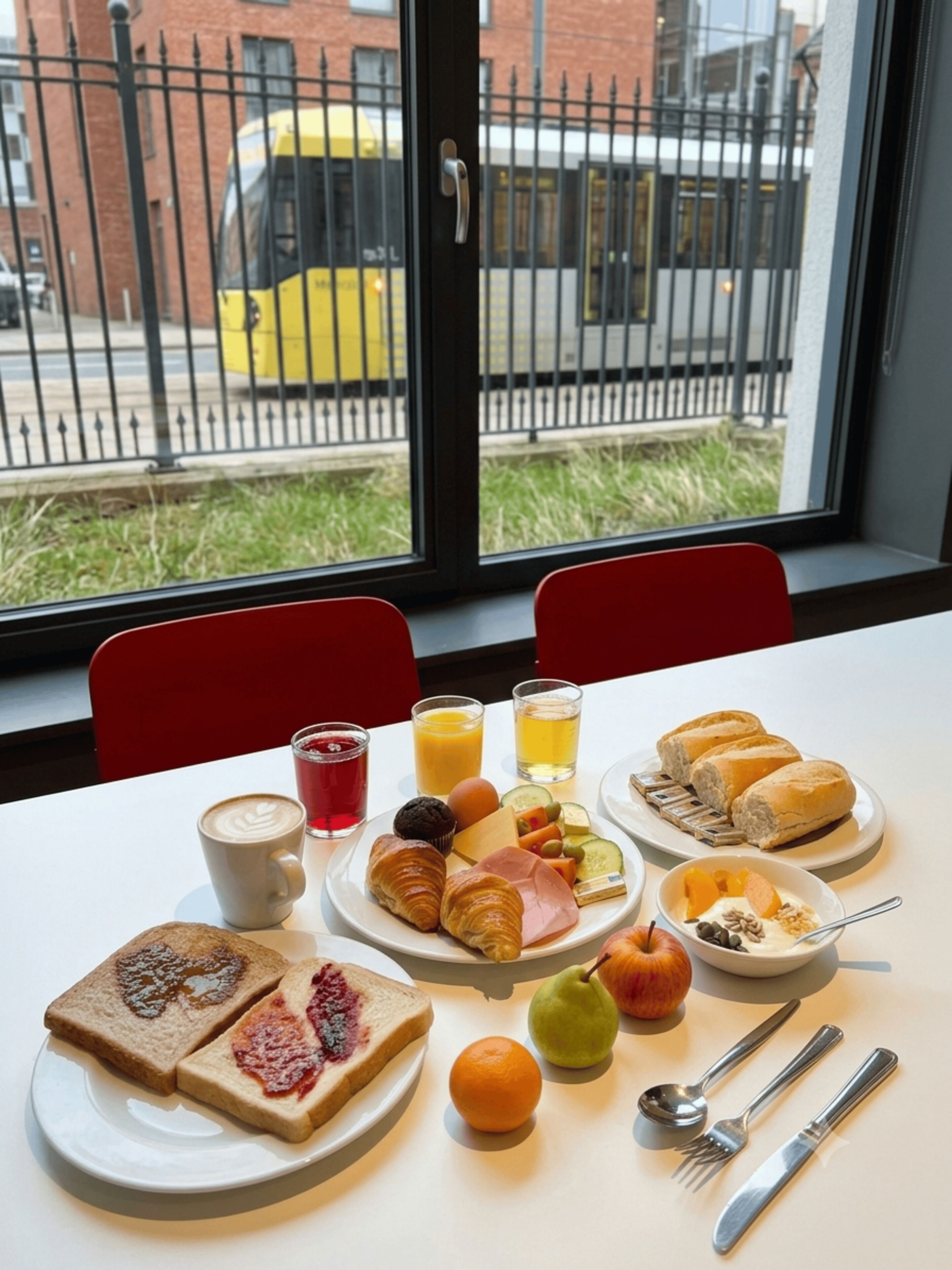 A breakfast table with croissants, toast, fruit, and beverages.