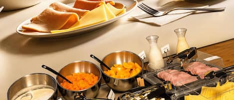 Un bufé con diversos alimentos, incluyendo frutas, quesos y carnes.
