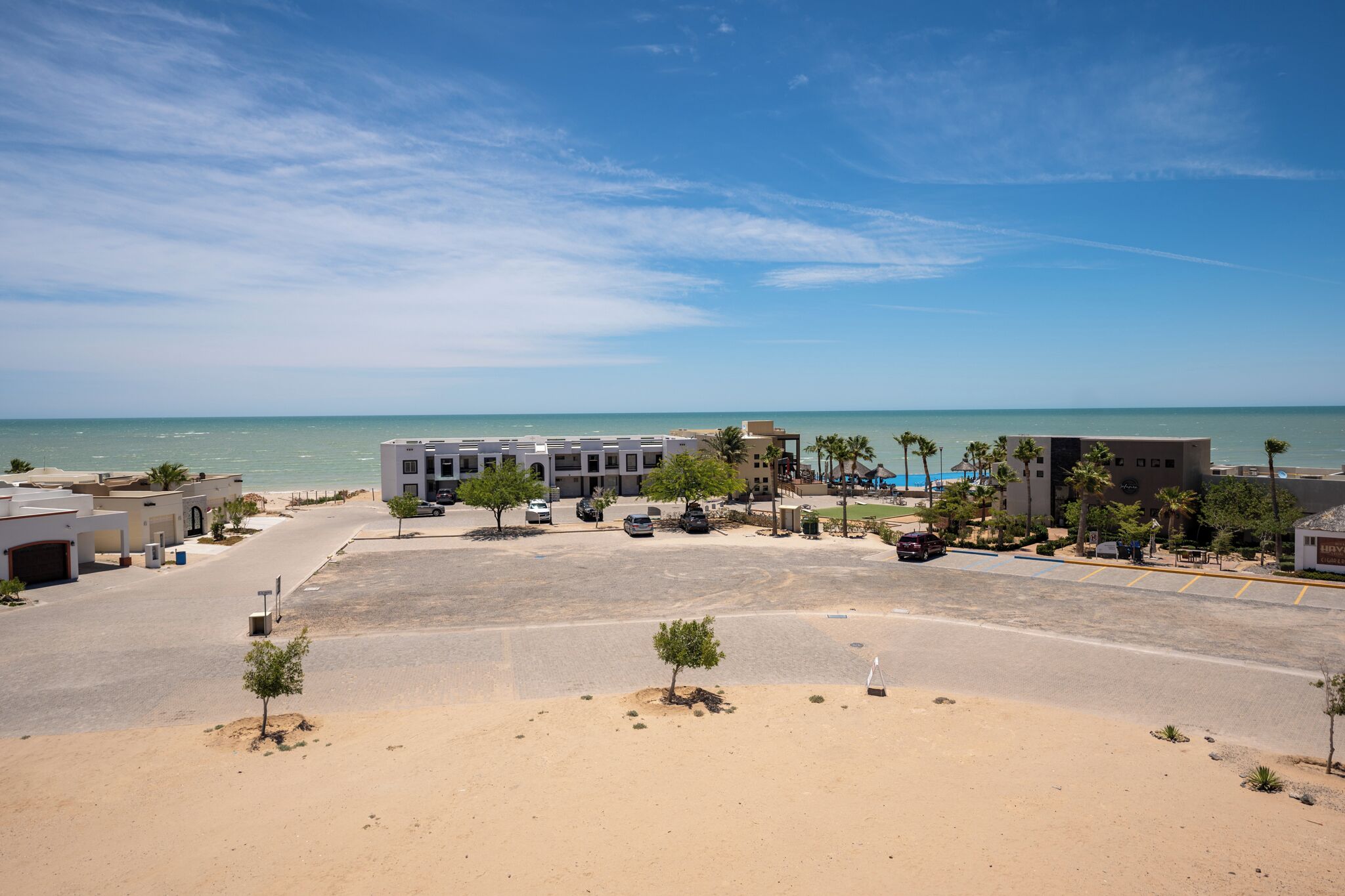 Ein Hotel an der Küste mit Parkplatz, Blick auf den Strand und moderner Architektur.