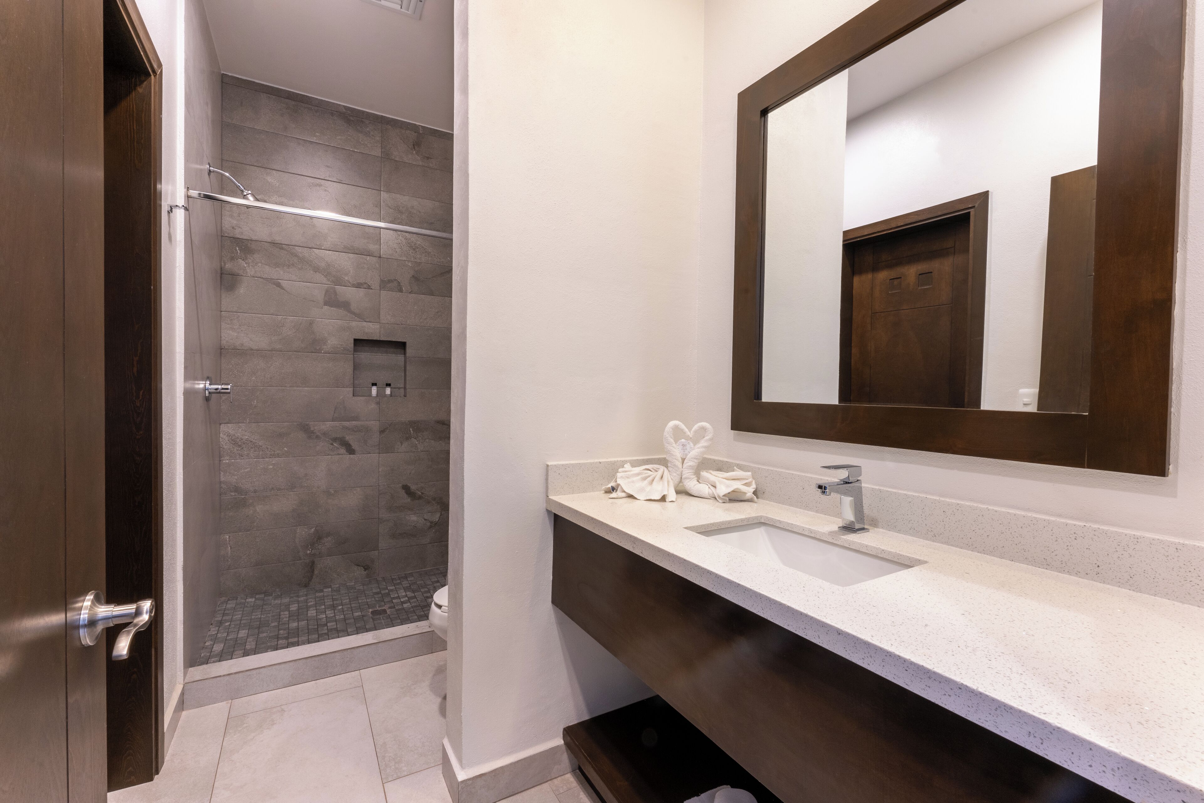 A modern bathroom with a shower, a sink, and a large mirror.