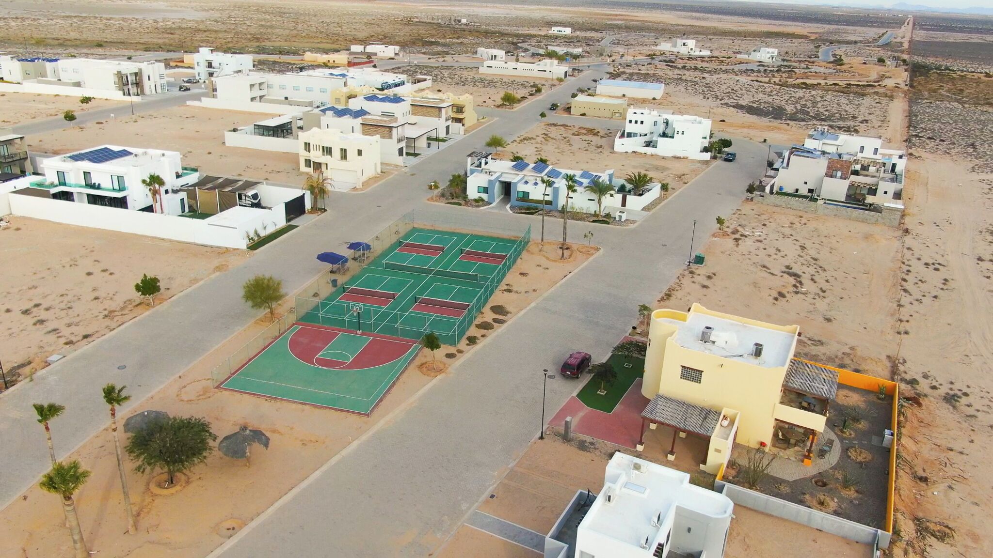 A residential area with modern houses, a basketball court, and a road.