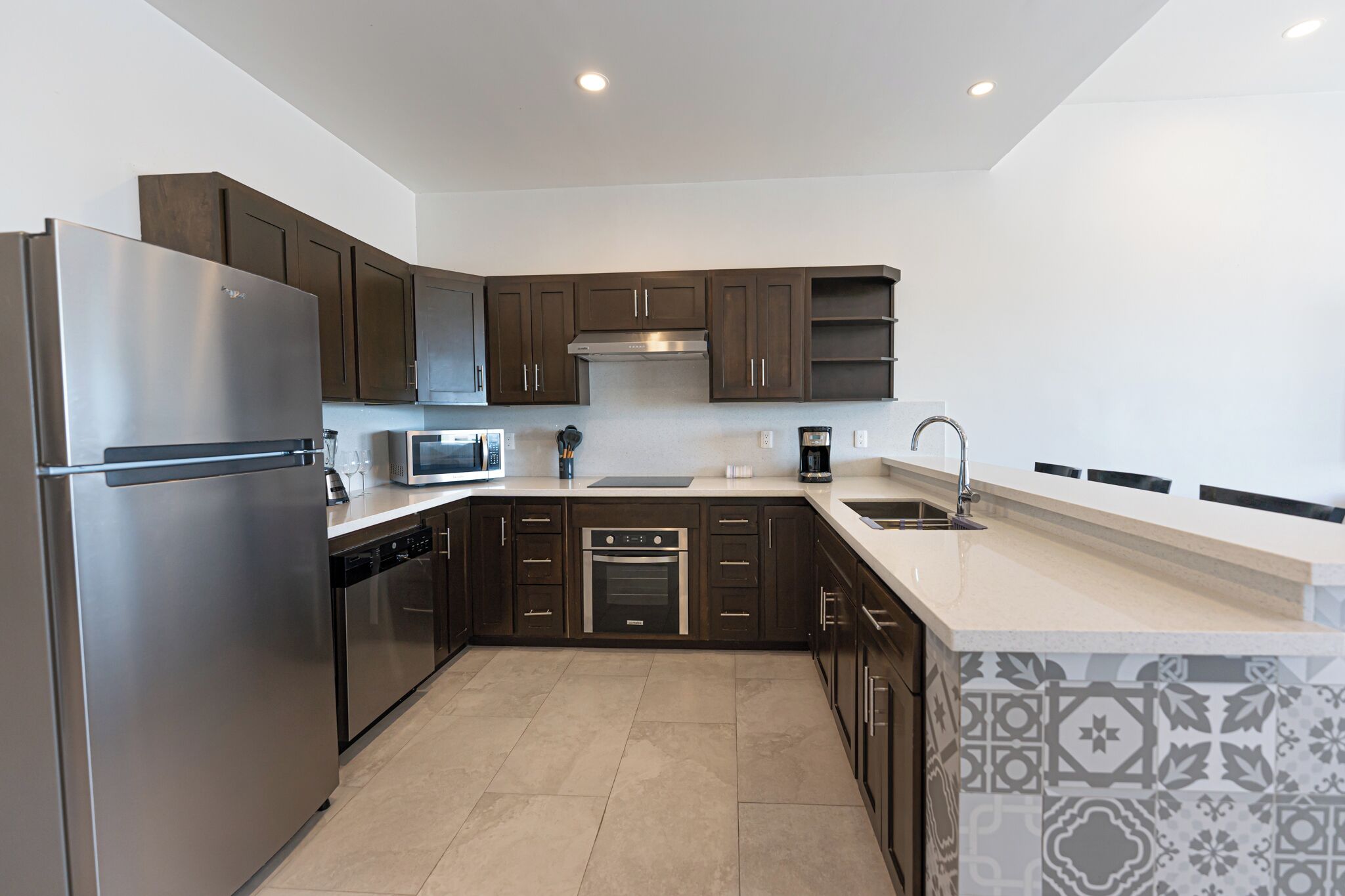 A modern kitchen with dark cabinets, stainless steel appliances, a microwave, and a built-in oven.