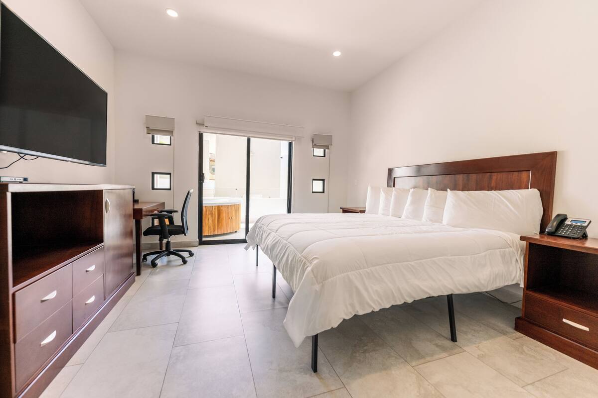 Een moderne hotelkamer met een groot bed, een bureau, een stoel, een televisie en een schuifpui naar het balkon.