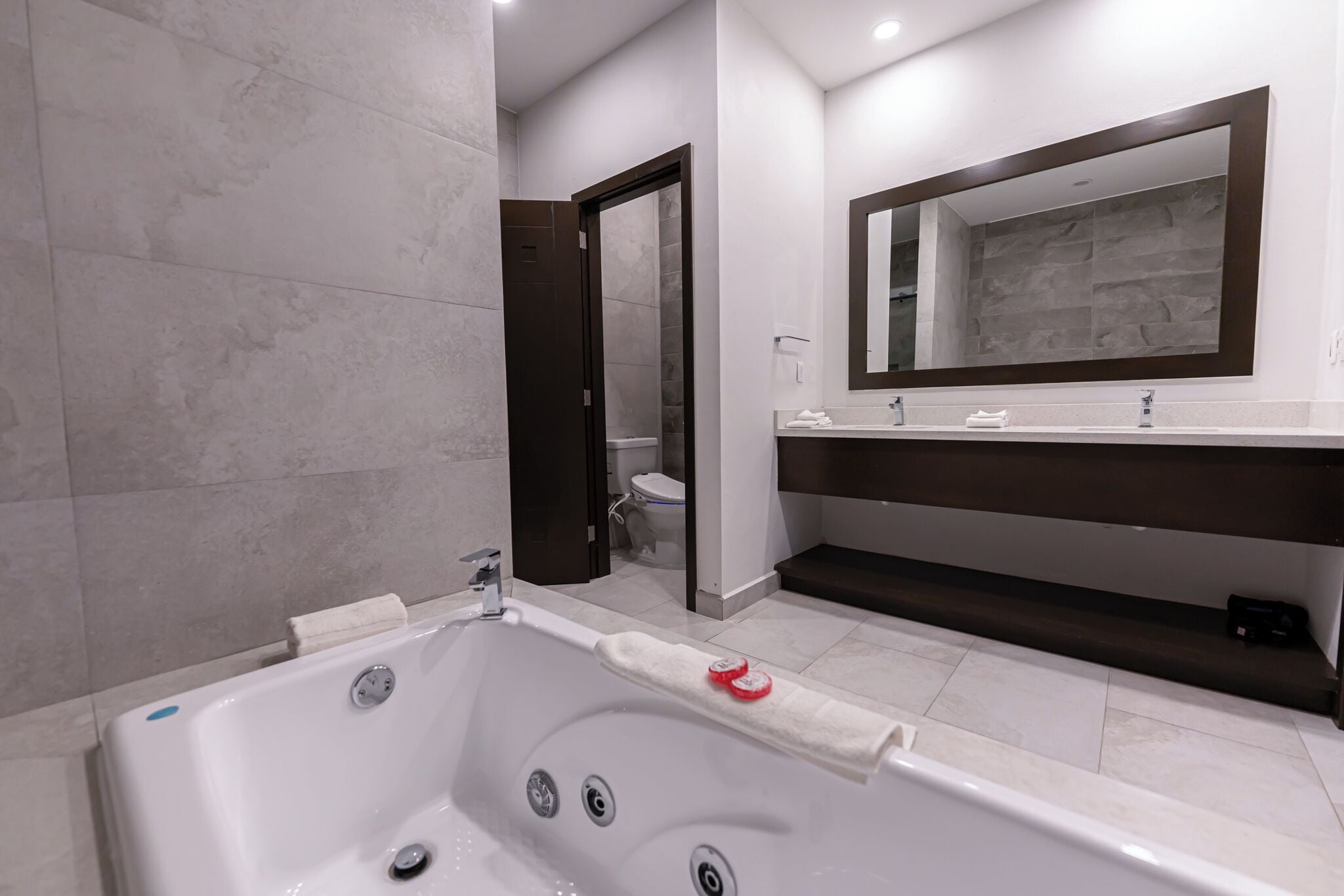 Un baño moderno con una bañera grande, un inodoro separado y un lavamanos con espejo.