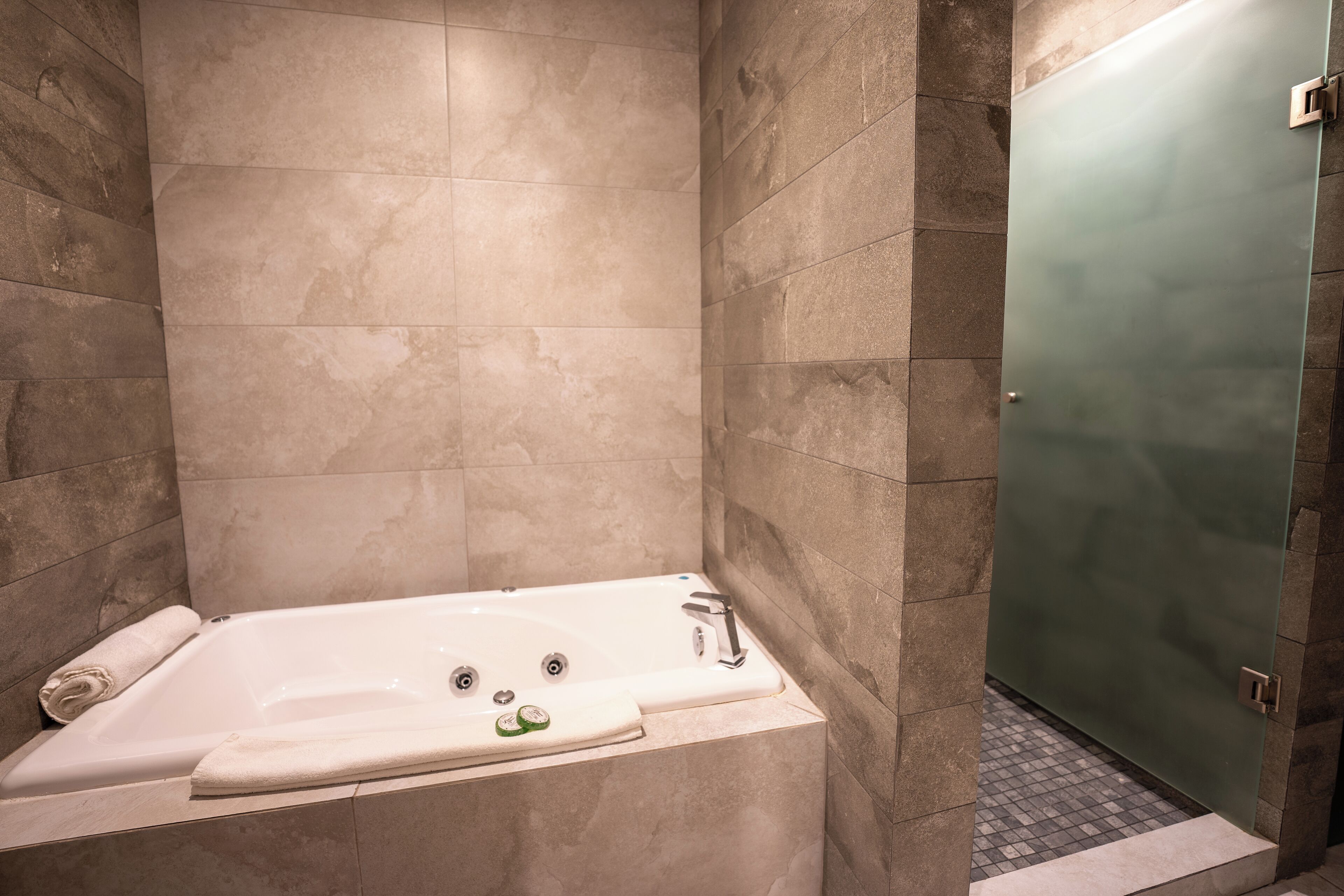 Une salle de bain moderne avec une baignoire sur pieds, une douche à parois de verre et un sol carrelé.