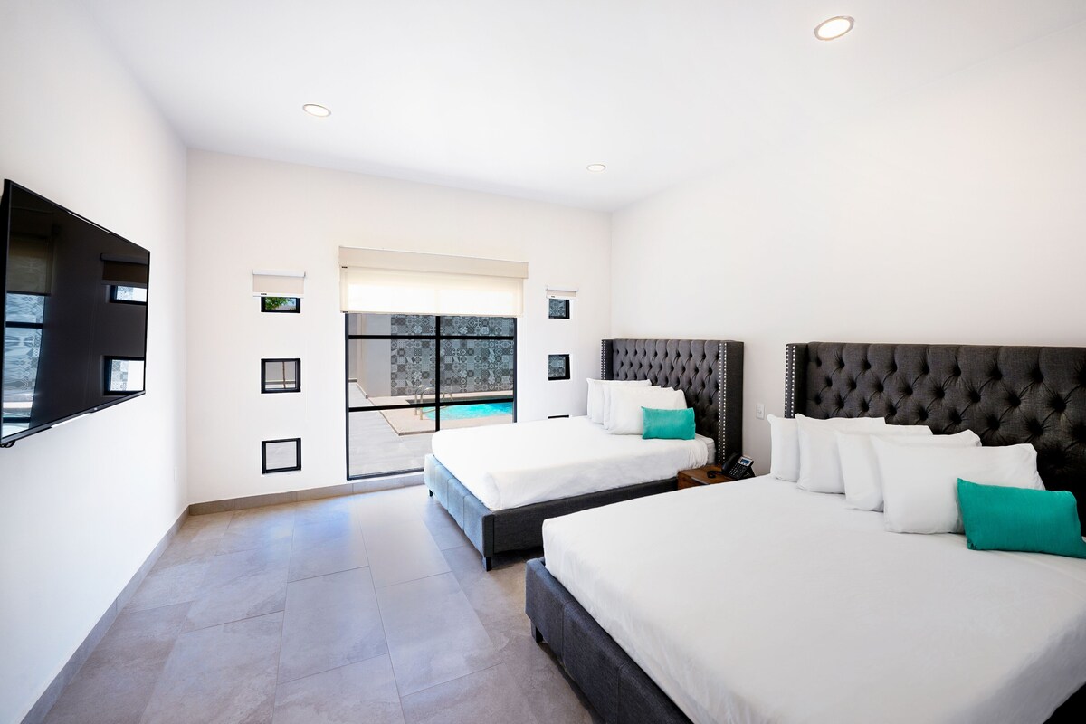 Ein modernes Hotelzimmer mit zwei Betten, einem großen Fenster und Blick auf einen Pool.