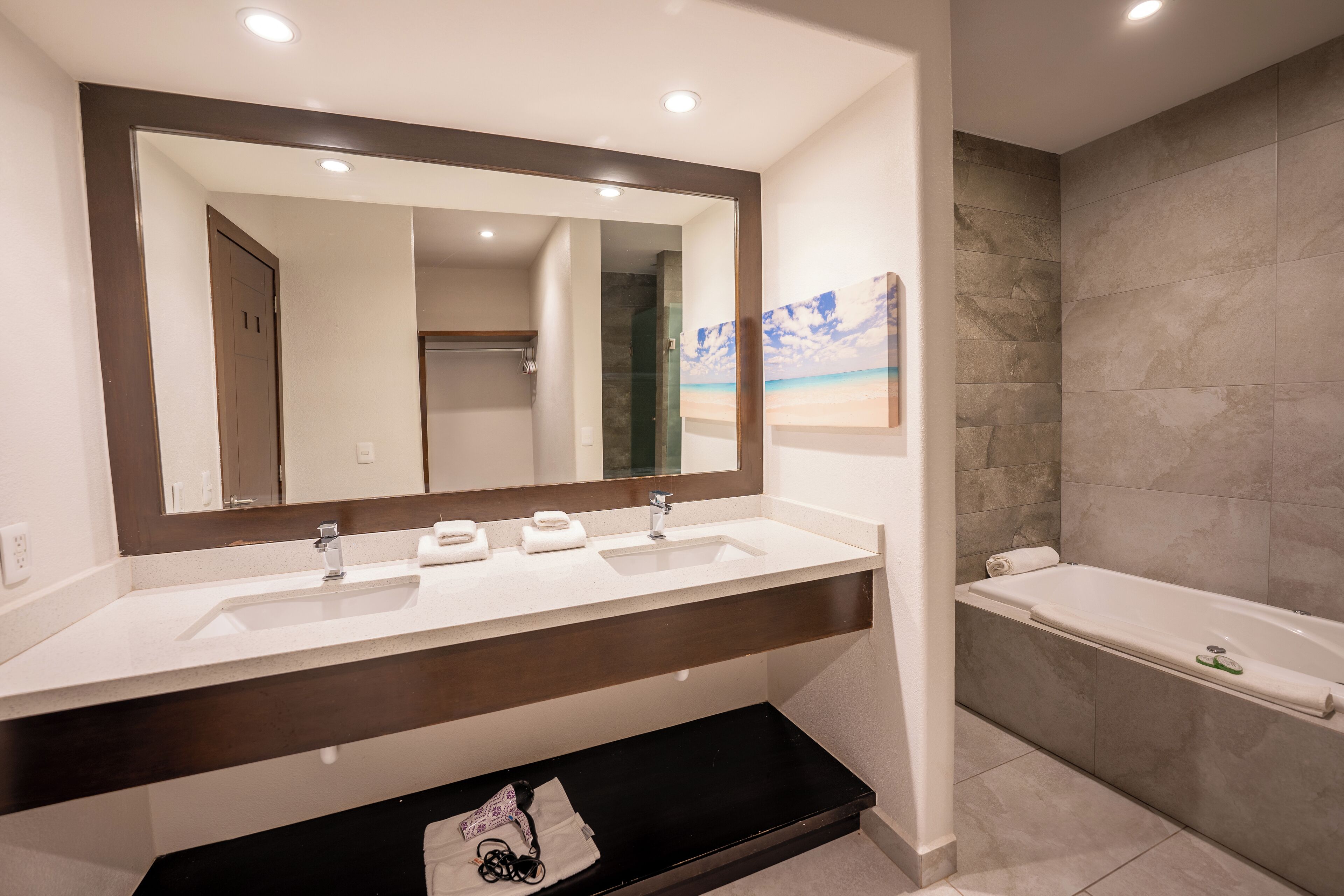 Une salle de bain moderne avec un meuble-lavabo à deux vasques, un grand miroir, une baignoire et un espace douche.