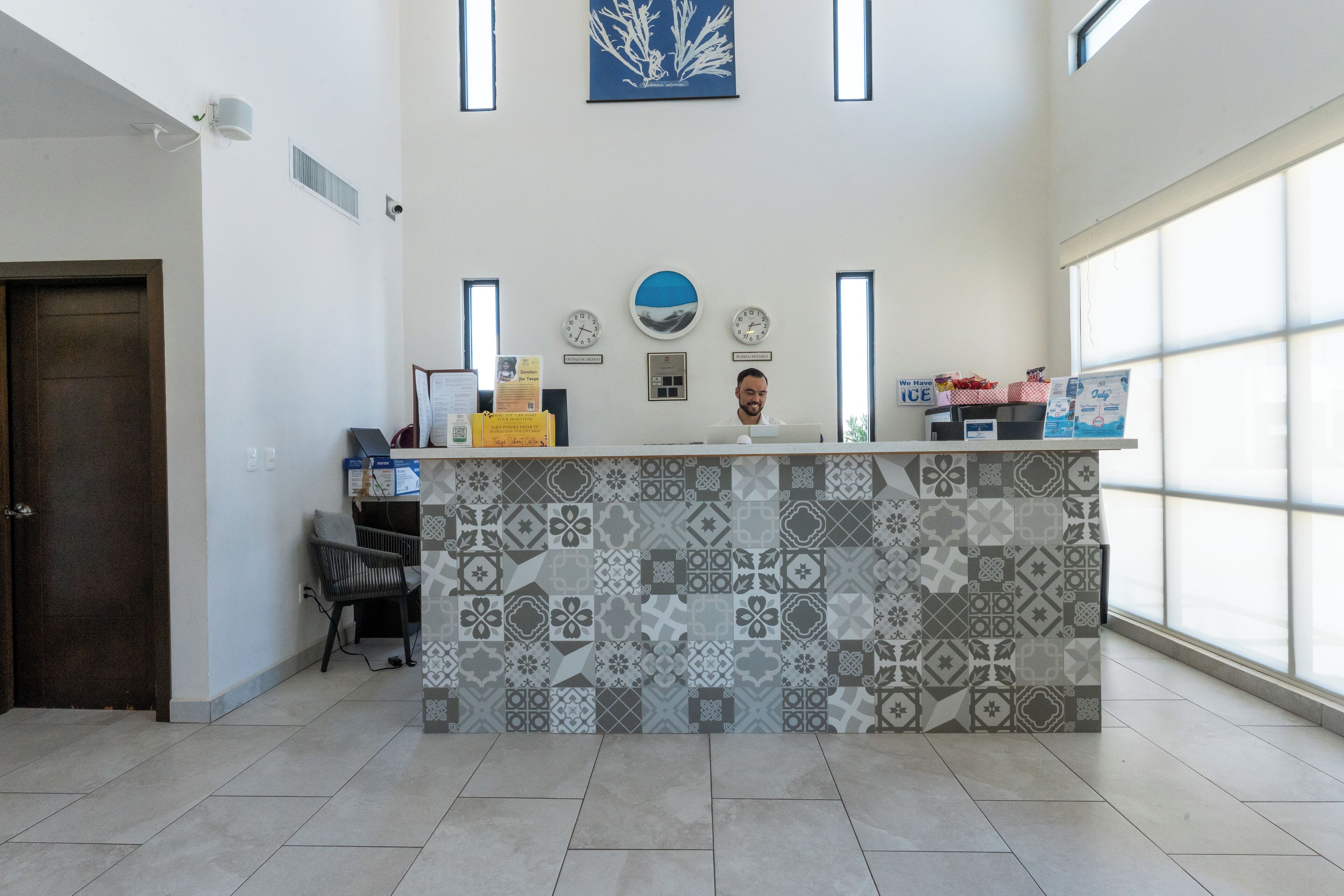 A reception area with a patterned tile counter, a clock, and a window with natural light.