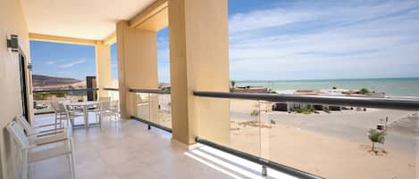 A balcony with a view of the beach and ocean.