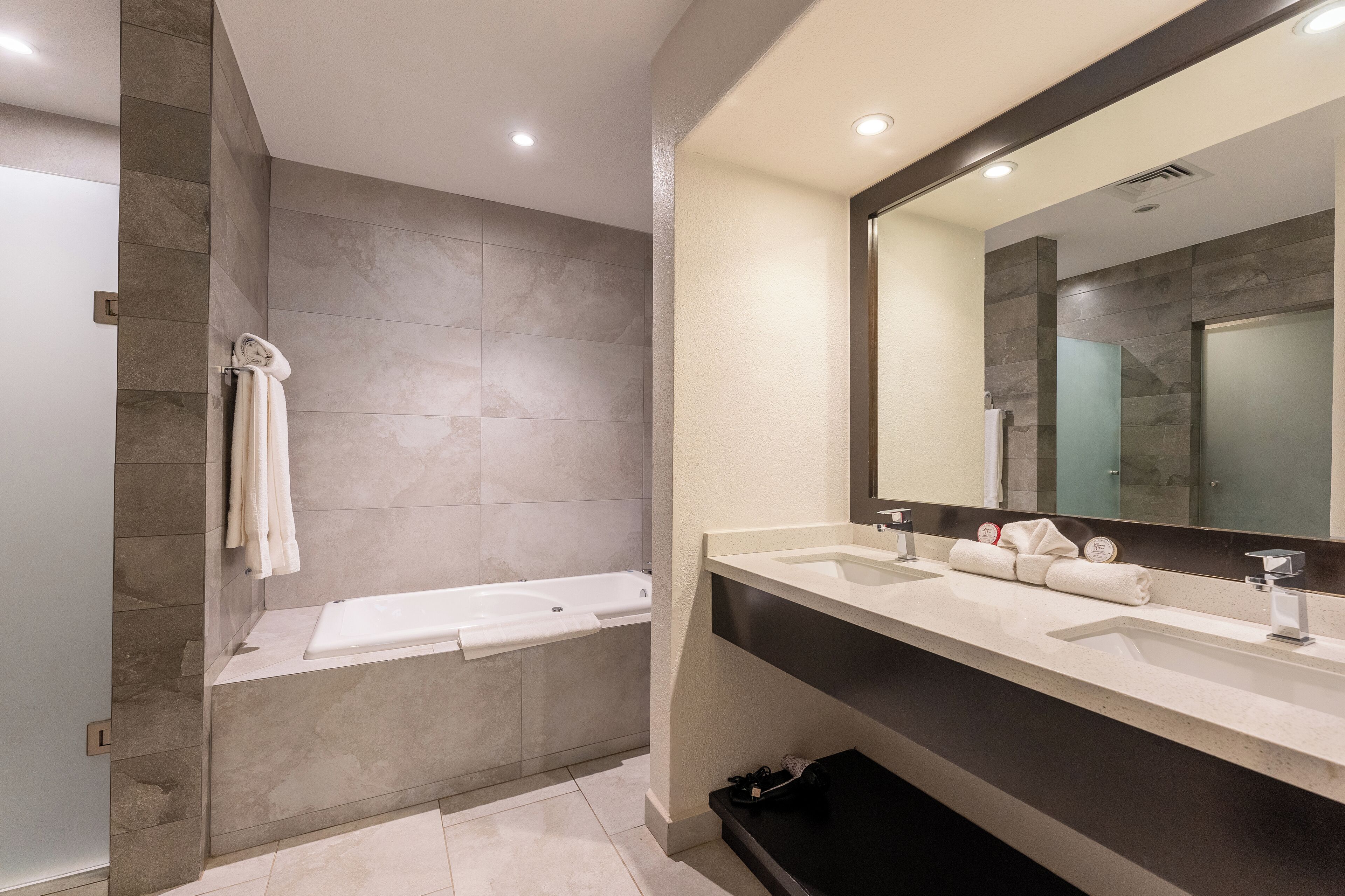 Une salle de bain moderne avec une baignoire, deux lavabos et un grand miroir.
