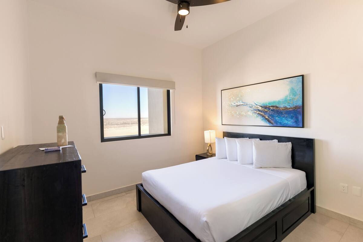 Een moderne hotelkamer met een groot bed, een bureau, een raam met uitzicht en een plafondventilator.
