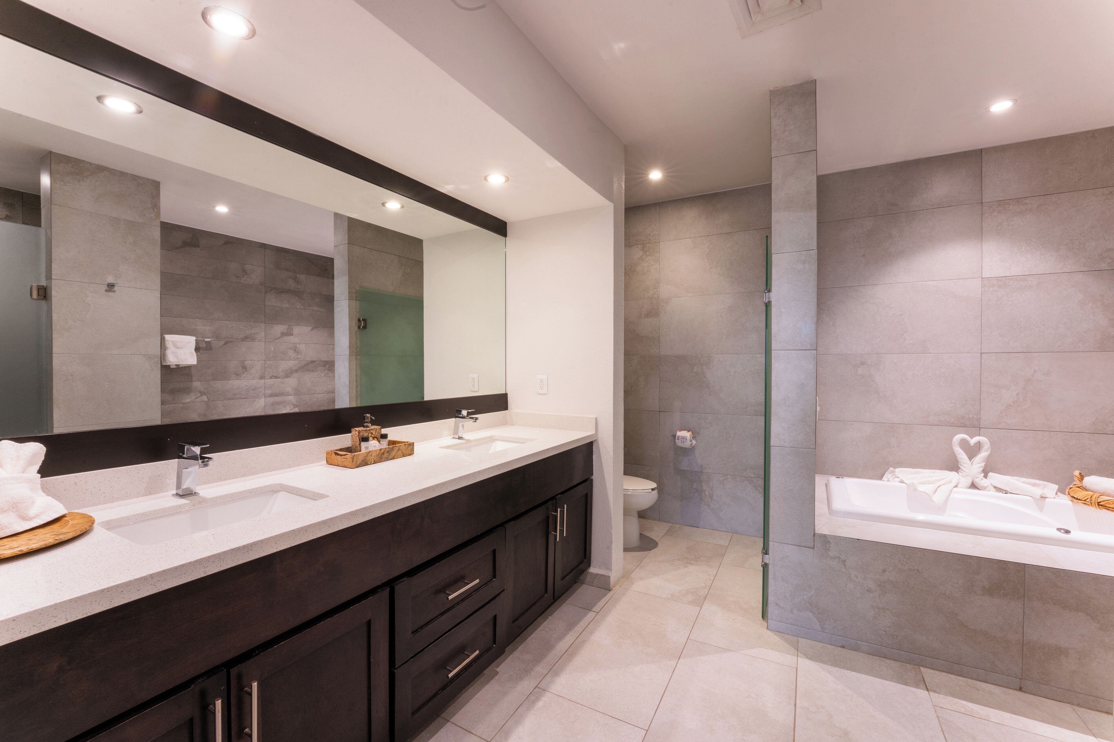 Un baño moderno con tocador doble lavabo, un espejo grande y zona de ducha.