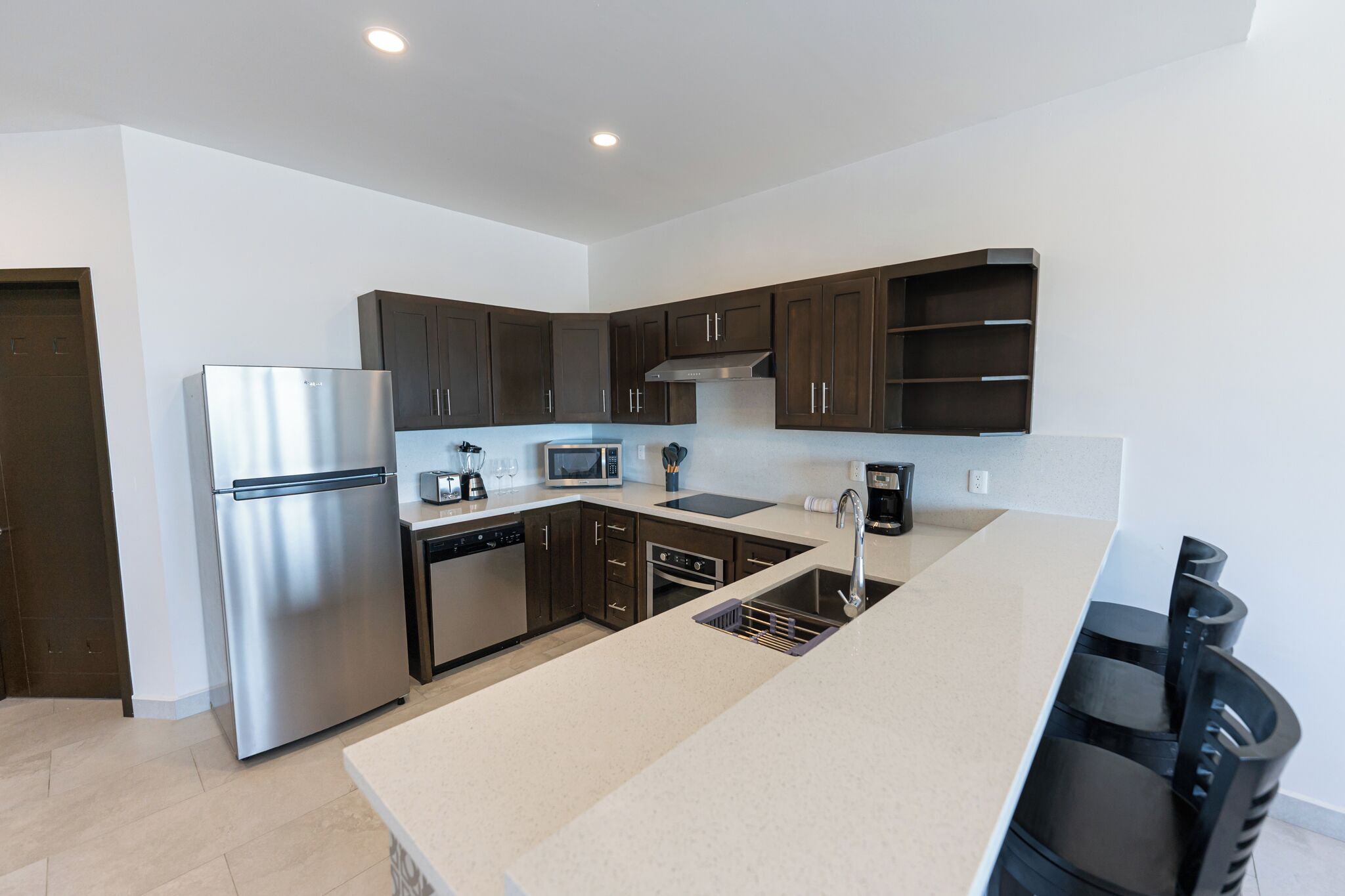 Una cocina moderna con electrodomésticos de acero inoxidable, armarios de madera oscura y una isla grande con un fregadero.