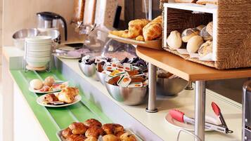 Un buffet proposant une variété de produits de boulangerie, notamment des pâtisseries et des muffins, disposés sur un comptoir recouvert d’un tapis vert.