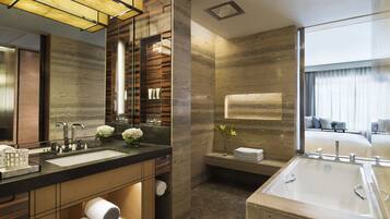 A modern bathroom with a large sink, mirror, and built-in shelves for towels.