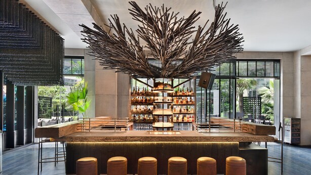 A modern bar area with a central island, bar stools, and a large decorative plant.